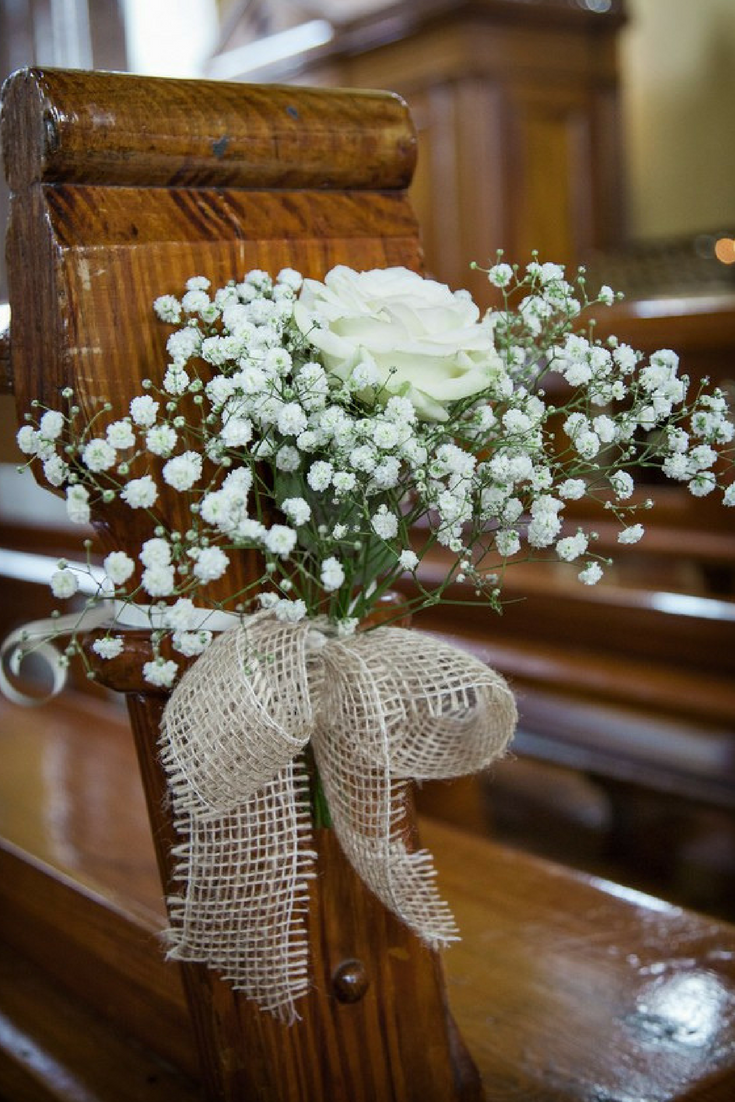 baby's breath bouquets with burlap bows hanging from pew for wedding